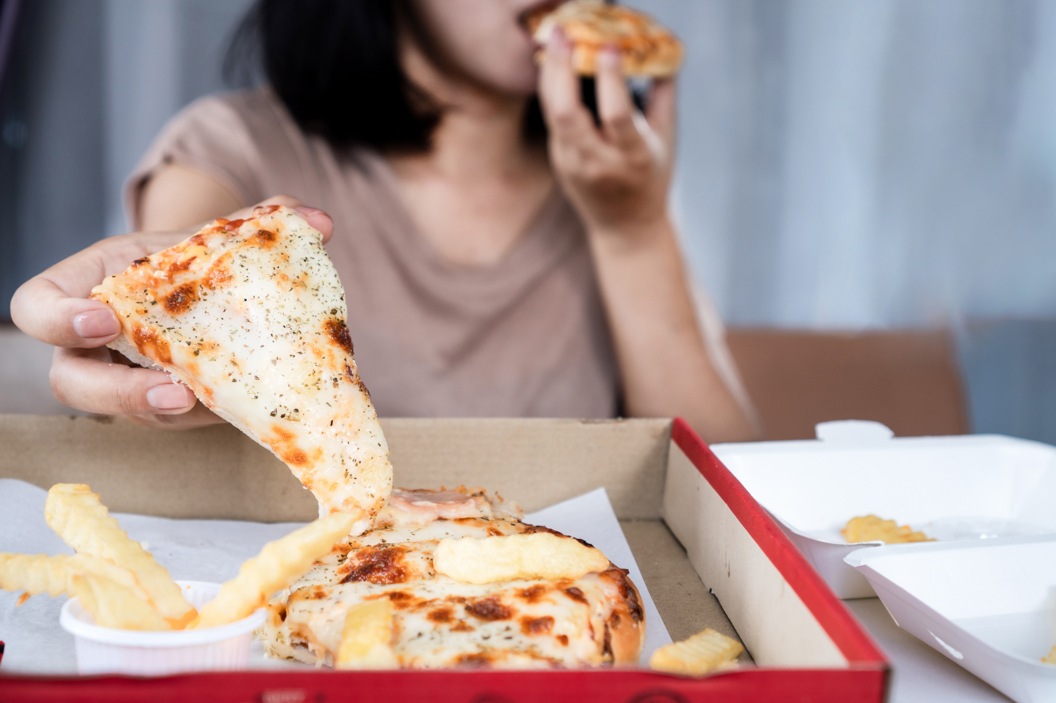 Binge eating disorder concept with woman over eating fast food